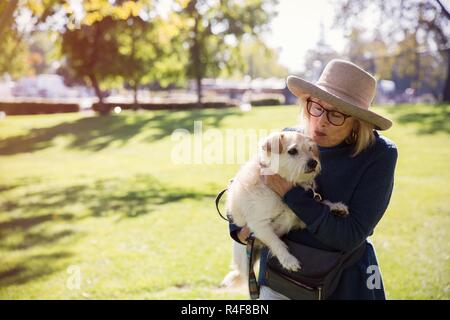 Un maturo donne baciare un cane in posizione di parcheggio Foto Stock