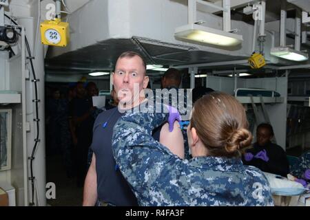 161025-N-UM082-007 NORFOLK (Ott 25, 2016) - Wasp-classe assalto anfibio nave USS Bataan (LHD 5), Delegato, Cap. Corey Keniston, riceve la sua influenza annuale shot all'interno del reparto di medicina. Bataan è in preparazione per una prossima distribuzione pianificata. (U.S. Navy foto di Sottufficiali di terza classe Raymond Minami/rilasciato) Foto Stock