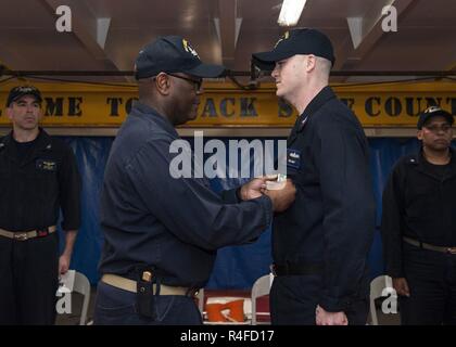 Golfo Arabico (1 maggio 2017) Lt. La Cmdr. Travis Arrington presenta il Navy e Marine Corps encomio Medal Boatswain compagno del 1° classe Chris Helms durante una cerimonia di messa in servizio a bordo della portaerei USS George H.W. Bussola (CVN 77) (GHWB). GHWB è distribuito negli Stati Uniti Quinta Flotta area di operazioni a sostegno della sicurezza marittima operazioni destinate a rassicurare gli alleati e partner e preservare la libertà di navigazione e il libero flusso di commercio nella regione. Foto Stock