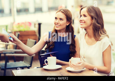 Le donne di pagare soldi al cameriere per un caffè al caffè Foto Stock