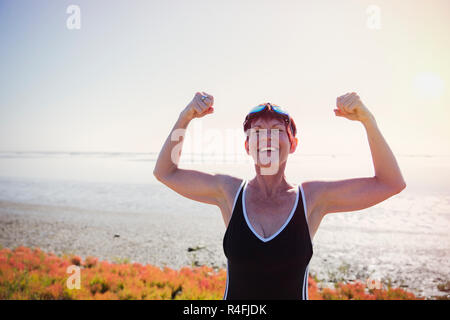 Vecchia donna flettendo i suoi muscoli Outdoor Foto Stock