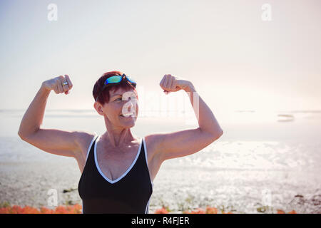 Senior donna che mostra i suoi muscoli Foto Stock