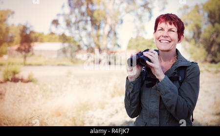 Sorridente donna Senior con il binocolo Foto Stock