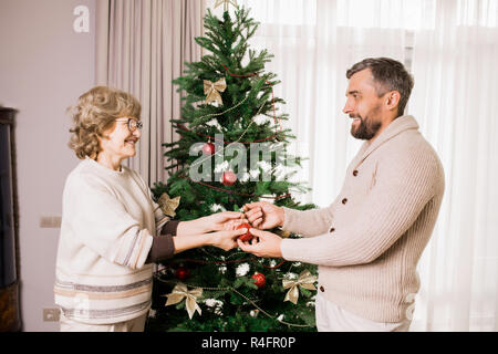 Senior donna albero di decorazione con figlio Foto Stock