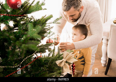 Little Boy decorare albero di Natale Foto Stock