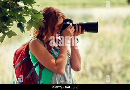 Giovane donna con zaino e fotocamera all'aperto Foto Stock