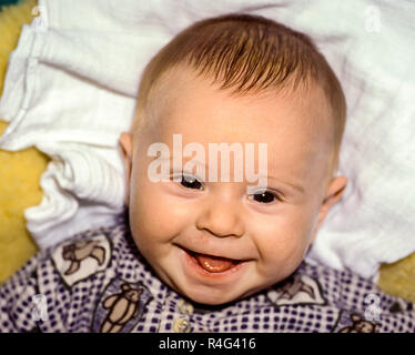 Il bambino che giace su una pelle di agnello sorrisi Foto Stock