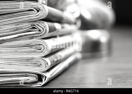 Pila di mattina freschi quotidiani sul tavolo in ufficio. Ultime notizie finanziarie ed economiche nel quotidiano. Le pagine con i dati. Piegato e riviste impilati Foto Stock