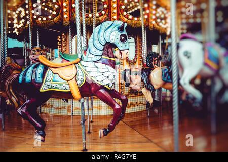 Antica giostra francese in un Holiday Park. Tre cavalli e aereo su un tradizionale fiera giostra vintage. Merry-go-round con i cavalli. Foto Stock