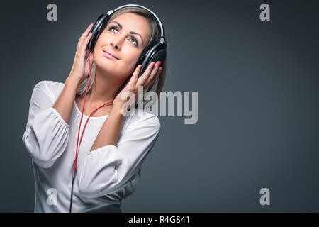 Piuttosto, giovane donna ascoltando la sua musica preferita su hi-fi cuffie, dancing, godendo la melodia, avente un momento per se stessa Foto Stock