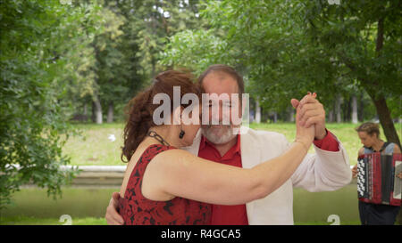 Positivo amici adulti dancing coppia danza in giardino. Coppia di anziani ballare il tango. Anziano uomo e donna dancing libertango. Foto Stock