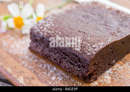 Brownie al cioccolato torta e Daisy Flower e versare sul tagliere o bordo di taglio sulla tavola di legno in stretta fino angolo Foto Stock