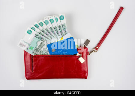 Portamonete rosso da cui fuoriesce il denaro e le carte di credito su sfondo bianco Foto Stock