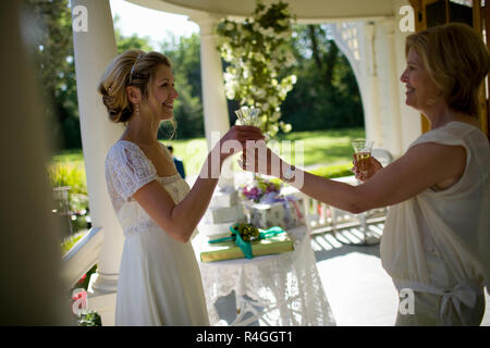 Sposa la condivisione con una bottiglia di champagne e sua madre il giorno del matrimonio Foto Stock