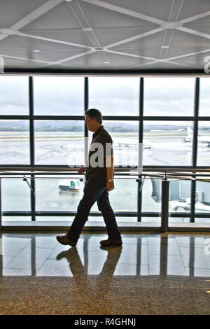 Uomo che cammina lungo in aeroporto Foto Stock