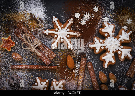 Natale o Capodanno sfondo di Gingerbread cookie, spezie, frutta con zucchero e fiocchi di neve. Vista dall'alto. Foto Stock