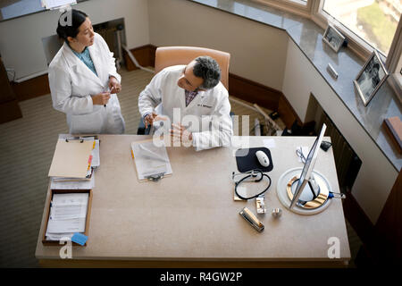 La metà degli adulti consulenza medico con un vecchio supervisore presso la loro pratica. Foto Stock