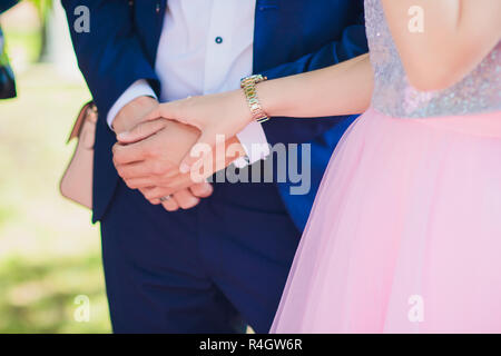 Bella coppia Giovane di un uomo e di una donna. Close-up di mano lo sposo e la sposa con un anello di nozze. Focus sul braccio e l'anello. sposa in abito bianco. La foto è stata ritagliata senza facce. Foto Stock