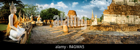 Fila di seduto statue di Buddha e le antiche rovine di templi. Foto Stock