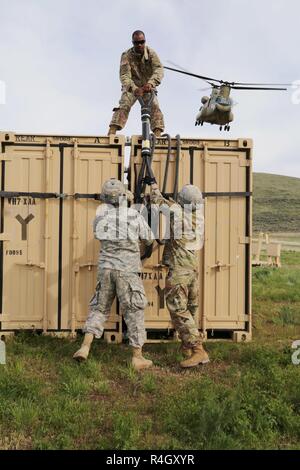 Stati Uniti Il personale dell'esercito Sgt. Chris Hearne, Air Assault istruttore dal Guerriero Fantasma Academy, assiste i soldati della 92ma Chemical Company, xxxiii battaglione chimico, 48th brigata chimica, preparare per il collegamento di un contenitore durante una imbracatura operazione di carico a Yakima Training Center, di Yakima, Washington, 5 maggio 2017. Imbracare il carico delle operazioni unità consentono di svolgere la loro missione dal rapido trasferimento di materiali di consumo e attrezzature, ignorando gli ostacoli di superficie. Foto Stock