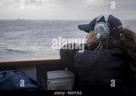 Oceano atlantico (sett. 28, 2018) marinaio Iliana Lemus sorge Porto lookout guarda sul Ponte del Ticonderoga-class guidato-missili cruiser USS la cittadella di Hue (CG 66) durante un esercizio con Royal Canadian Navy Halifax-fregate della classe HMCS Halifax (FFH 330) e HMCS Toronto (FFH 333). La cittadella di Hue è attualmente in corso su un pianificate regolarmente la distribuzione. Foto Stock