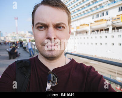 Giovane fa selfie vicino a una nave da crociera. Foto Stock