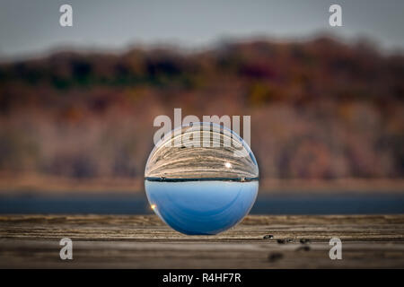 Una foto di vetro sfera seduto su di un molo di legno in Virginia che riflette il sole del mattino. Foto Stock