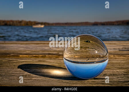 Una foto di vetro sfera seduto su di un molo di legno in Virginia che riflette il sole del mattino. Foto Stock