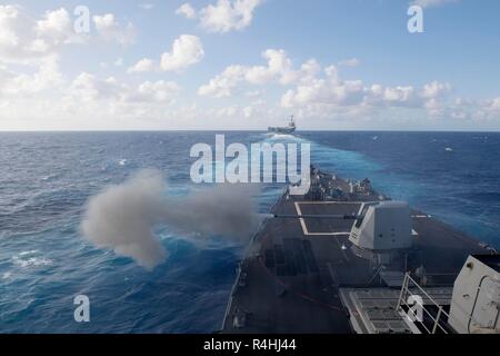 181118-N-GC639-1048 Mare delle Filippine (nov. 17, 2018) Il Arleigh Burke-class guidato-missile destroyer USS Spruance (DDG 111), il primo piano, incendi di una MK 45 da 5 pollici la pistola mentre la vela in formazione dietro il Nimitz-class portaerei USS John C. Stennis (CVN 74) durante un live fire evoluzione. John C. Stennis e Spruance sono attualmente in corso e condurre operazioni in acque internazionali come parte di un vettore doppio sciopero vigore esercizio. Gli Stati Uniti Marina ha pattugliato l'Indo-Pacifico regione di routine per più di 70 anni di promuovere la sicurezza regionale, la stabilità e la prosperità. (U.S. Foto di Marina di Massa organi giurisdi Foto Stock