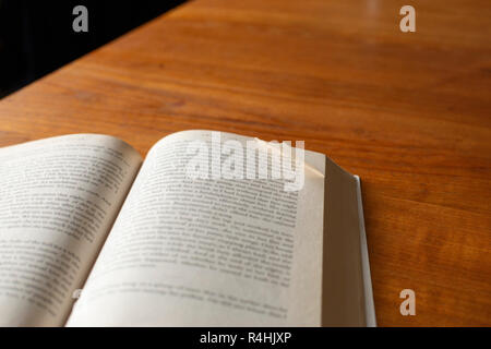 Un cane dalle orecchie pagina in un paperback su un tavolo di legno Foto Stock