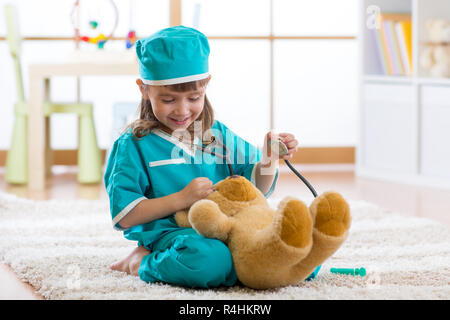 Bambino sorridente ragazza che gioca con Teddy bear e fingere lei è un dottore in ospedale Foto Stock