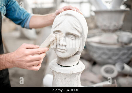 Scultore lavora con la scultura della testa femmina di pulizia con spazzola nel vecchio studio. Vista ravvicinata con nessun volto Foto Stock