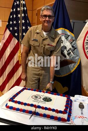 Il cap. Adam Armstrong, Commander, Naval Medical Research Center (NMRC), tagli un pezzo di torta per festeggiare NMRC's 76th compleanno. Foto Stock