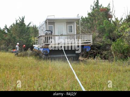 Risolvere Marine Group tecnici di soccorso tirare un spostato houseboat da Rachel Carson riservare una linea dedicata di preservare la natura e torna verso Taylor Creek, Carteret County, N.C., Sabato, Ottobre 27, 2018. Il FSE-10 comando unificato, composta di Stati Uniti Coast Guard, North Carolina Wildlife risorse Commissione, North Carolina e Dipartimento di Qualità Ambientale, ha collaborato con la ditta di recupero risolvere Marine Group e più agenzie di assistenza per ridurre l'inquinamento da affondata o spostato le navi in fragili aree ambientali dopo l uragano Firenze. Foto Stock