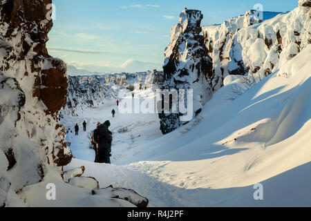 La gente a piedi attraverso il Continental Divide, Thingvellir national park, Islanda. Luminosa e soleggiata giornata con cielo blu cobalto Foto Stock