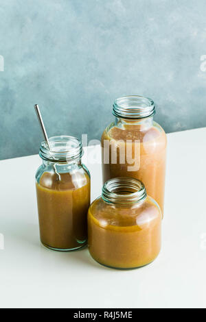 Diversi tipi di bicchieri con freschi Pompelmi, kiwi, persimmon e lampone frullati. sul tavolo bianco e lo sfondo blu. cibo sano. mattina bre Foto Stock