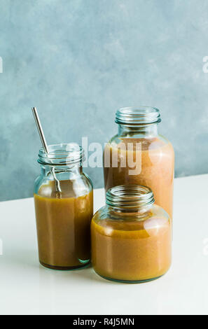 Diversi tipi di bicchieri con freschi Pompelmi, kiwi, persimmon e lampone frullati. sul tavolo bianco e lo sfondo blu. cibo sano. mattina bre Foto Stock