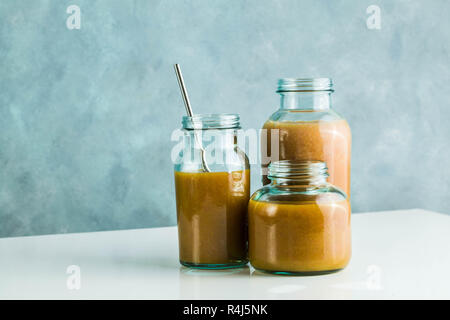 Diversi tipi di bicchieri con freschi Pompelmi, kiwi, persimmon e lampone frullati. sul tavolo bianco e lo sfondo blu. cibo sano. mattina bre Foto Stock