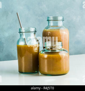 Diversi tipi di bicchieri con freschi Pompelmi, kiwi, persimmon e lampone frullati. sul tavolo bianco e lo sfondo blu. cibo sano. mattina bre Foto Stock