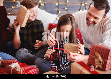 Dei bambini felici apertura regalo di Natale con i genitori Foto Stock