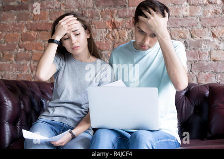 Scioccato giovane coppia in cerca di documenti e laptop. Foto Stock