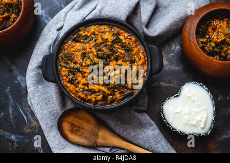 Spinaci con riso in pot nero su sfondo scuro Foto Stock