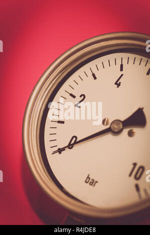 Manometro su sfondo rosso Foto Stock