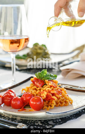 Luce di pasta pranzo con un bicchiere di vino rosato, versando fresca Olio di oliva Foto Stock