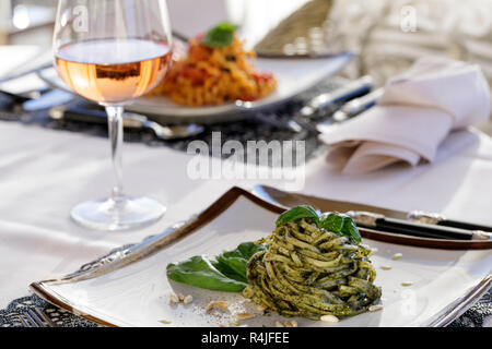 Luce di pasta pesto il pranzo con un bicchiere di vino rosato Foto Stock