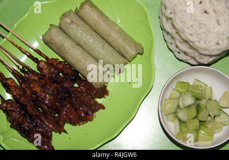 Piatto di riso dolci (lontong) con saté bastoni. Foto Stock