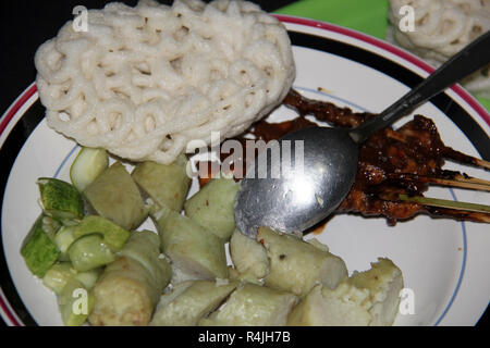 Piatto di riso dolci (lontong) con saté bastoni. Foto Stock