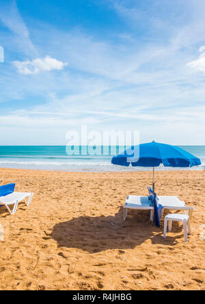 Blue ombrelloni e sdraio in spiaggia deserta Foto Stock