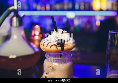 Frullato con ciambelle. Latte cocktail blu sissy si erge sulla tavola del cafe su sfondo scuro. Foto Stock