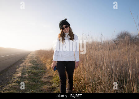 Giovane donna in piedi su un vuoto e strada di nebbia al mattino presto Foto Stock